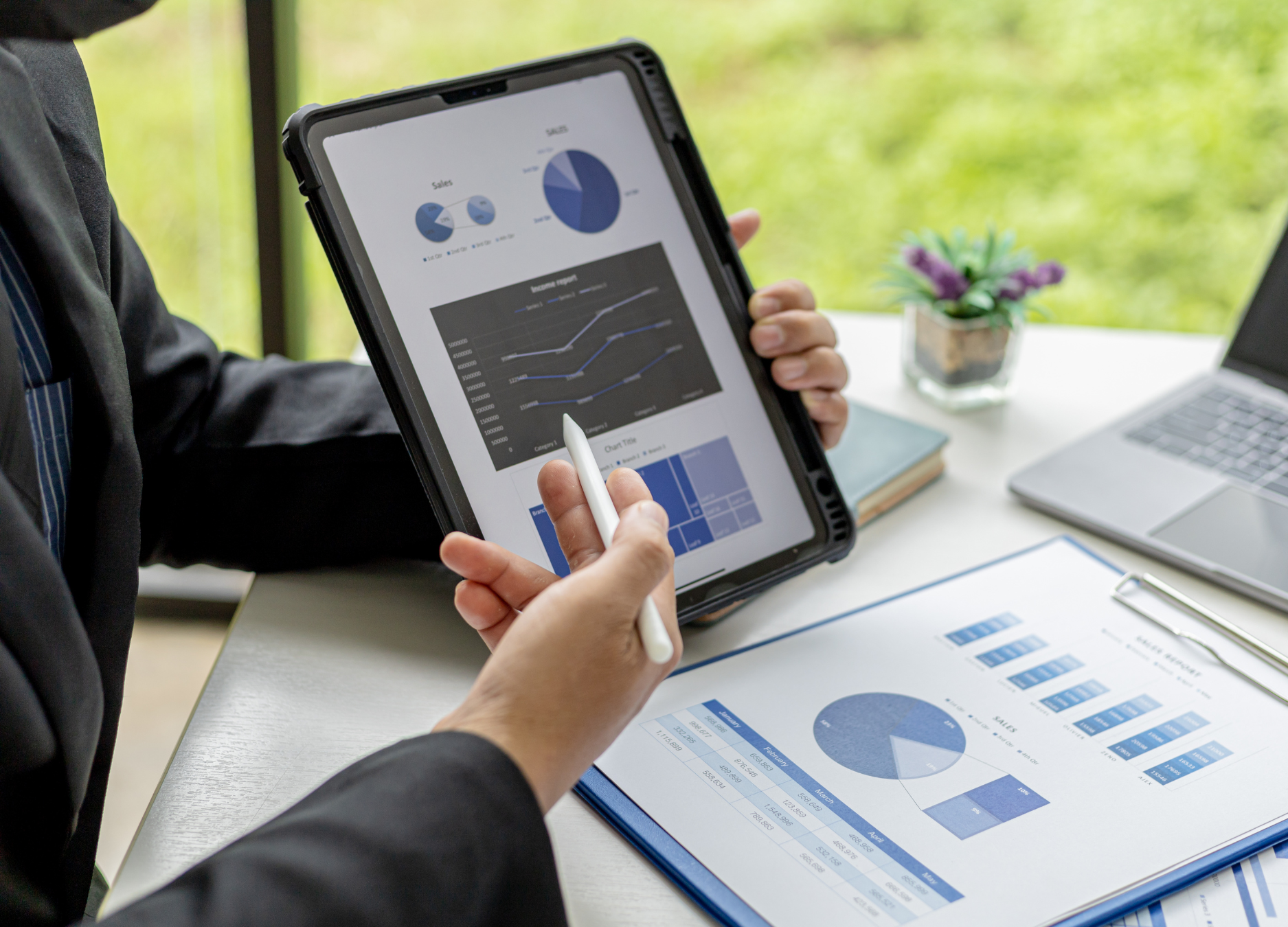 Profissionais analisando gráficos e dados em tablet e planilhas, representando o alinhamento entre marketing e vendas com foco em performance e metas.